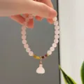 Close-up detail of the pink crystal beaded bracelet featuring a delicate gourd pendant. - Lotus Pod