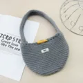 Primo piano dettagliato della bellissima borsa in morbida lana grigia con bottone. - Grigio