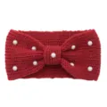Detailed close-up of a red knitted wool headband adorned with elegant white faux pearls. - Jujube Red