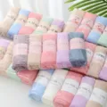 Detailed shot of soft colorful coral fleece towels rolled neatly with custom paper belly bands. - Set of 5