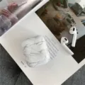 Detailed close-up of marble pattern AirPods protective case on magazine flatlay background. - White / AirPods Pro