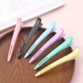 Close-up detail of colorful duckbill hair clips arranged neatly on a wooden tray for styling. - 1 Piece / Black