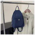 Detailansicht eines dunkelblauen Nylon-Mini-Rucksacks mit Fronttasche am Kleiderständer. - Blau