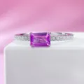 Detailed shot of a minimalist pink emerald cut gemstone ring with sparkling side stones. - Size 5 / Pink
