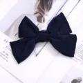Primer plano de una elegante pinza de pelo con lazo de terciopelo azul oscuro, textura delicada. - Azul Marino (Pinza de Pelo)