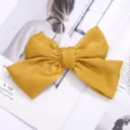 Vista detallada de una elegante pinza para el pelo con lazo de tela amarilla, accesorio chic. - Amarillo (Pinza de Pelo)