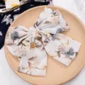 Detail shot of a sweet floral chiffon hair bow clip, elegant spring hair accessory for women. - Premium White Yellow Floral