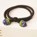 Detailed view of a black hair tie featuring rhinestone embellished berry ends for women. - Royal Blue Strawberry