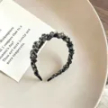 Detailaufnahme eines plissierten Blumenhaarreifens mit Innenzähnen für Damen-Haarstyling. - Blumen