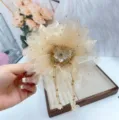 Vue de détail de la pince à cheveux fleur en résille champagne avec de magnifiques pompons. - 11cm / Champagne