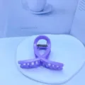 Gros plan d'une pince à cheveux violette douce avec une élégante boucle pour chignons. - Violet