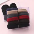 Gros plan d'élastiques à cheveux épais et élastiques en boîtes transparentes, couleurs variées. - Style Rayé Droit Foncé