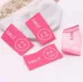 Close-up detail of pink woven smiley face fabric labels, perfect for DIY hair accessories. - 1 Piece / Rose Red