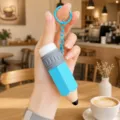 Close-up detail of the creative pencil shaped keychain pendant held in hand at a cafe table. - Blue