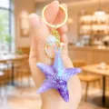 Detailed view of a trendy purple holographic starfish keychain with a white pearl and gold ring. - Iridescent Starfish Keychain (Purple)
