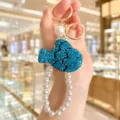 Exquisite detail view of the sparkling rhinestone blue fish keychain with pearl string. - Lake Blue