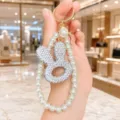 Detailed close-up view of a sparkling rhinestone rabbit head keychain with pearl strap. - Hollow Rabbit Head Pearl Chain (White)