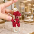 Detailed view of a sparkly red crystal giraffe keychain with elegant pearl string design. - Rhinestone Giraffe with Pearl Chain Style / Red