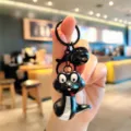 Detail view of a funny black cartoon snake keychain pendant with a bell for bags. - Glowing Little Snake - Black