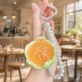 Detailed close-up of the simulated peeled orange pearl keychain with citrus texture. - Simulation Orange (Cyan)