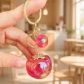 Close-up of cute persimmon resin keychain bag charm with gold hardware, aesthetic accessory. - Acrylic Good Things Happen (Red)
