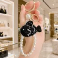 Detailed close-up of the elegant black crystal fish keychain with pearl strap design. - Black