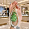Close-up detail of luxury rhinestone pineapple keychain with elegant pearl strap pendant. - Pineapple Pearl Strap Style / AB Green