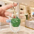 Detail view of the luxury green crystal apple keychain with elegant pearl bracelet. - AB Green