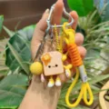 Cute toast bread keychain with braided lanyard and cartoon pendant details, close-up view. - Yellow