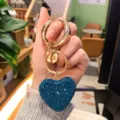 Portachiavi con cuore in strass blu e anelli dorati, ciondolo borsa elegante in metallo. - Blu Pavone