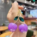 Detailed shot of the stylish cherry keychain with purple fruit and green crystal leaves. - Purple Iridescent Green Leaf Cherry