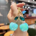 Charming crystal cherry keychain and bag charm with vibrant iridescent blue fruit details. - Blue Iridescent Green Leaf Cherry