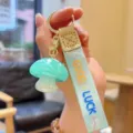 Close-up of glossy mint green resin mushroom keychain with lucky strap pendant detail. - Light Green Jelly Mushroom
