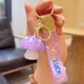 Close-up of a cute purple jelly mushroom keychain with golden hardware and fabric strap. - Purple Jelly Mushroom