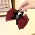 Vue détaillée de la pince à cheveux en filet rouge vin avec nœud noir et strass étincelants. - 8cm / Rouge