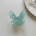 Gros plan détaillé de la pince à cheveux papillon bleue irisée avec une texture translucide. - Pince à Cheveux Papillon en Acétate Verte