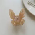 Vue détaillée de la pince à cheveux papillon en acétate translucide, texture élégante. - Pince à Cheveux Papillon en Acétate Champagne