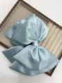 Detailed close-up of a large satin bow hair clip in ice blue, elegant design for styling. - Blue
