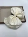 Vue détaillée de pince à cheveux nœud en satin crème, élégant accessoire en tissu. - Beige