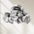 Gros plan détaillé montrant la texture satinée argentée lisse et les délicats plis de la pince. - Gris