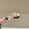 Gros plan détaillé de la pince à cheveux fleur en résine vintage avec des perles. - Beige