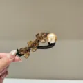 Gros plan détaillé de l'épingle à cheveux fleur en acétate rétro avec perle et strass. - Café
