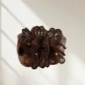Vue détaillée de la pince à cheveux en organza marron avec des accents dorés. - Café