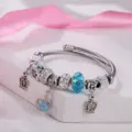 Dettaglio ravvicinato del bracciale rigido in argento con perline di cristallo e ciondoli a corona. - Corona Blu