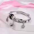 Vista dettagliata del bracciale rigido regolabile in acciaio con pendenti a corona e strass. - Nero