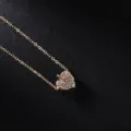 Scatto dettagliato di una delicata collana con ciondolo a foglia dorata e strass scintillanti. - Oro Bianco
