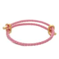 Primo piano del bracciale in pelle intrecciata rosa con chiusura in metallo dorato, elegante. - Rosa