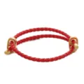 Primo piano dettagliato di un bracciale in pelle intrecciata rossa con estremità in metallo. - Rosso