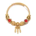 Primo piano dettagliato del bracciale rigido dorato con perline di cristallo rosso e ciondolo. - Rosso