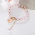 Primo piano dettagliato del braccialetto di cristallo rosa con ciondolo a margherita e perle - Rosa